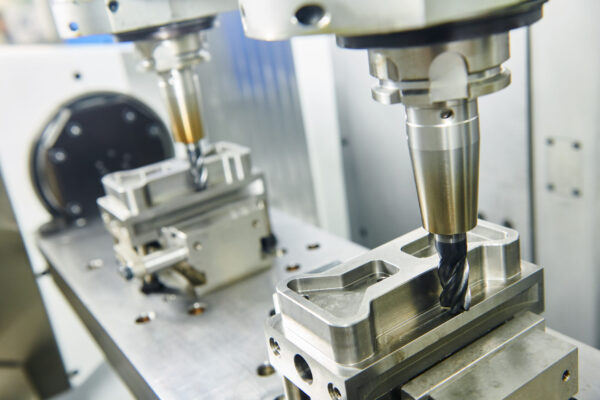 CNC machining cell with two shrinkfit milling tool holders milling the profile of metal parts.